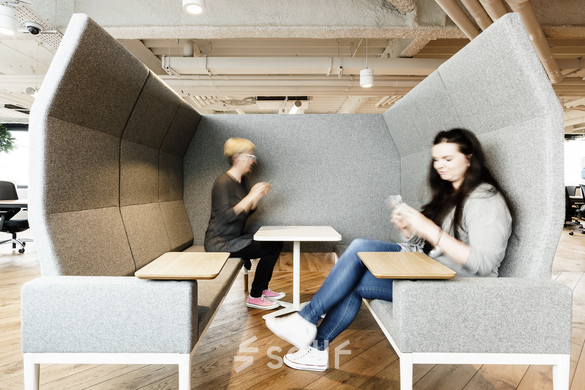 Two individuals are engaged in discussion in a cozy, modern meeting pod in an office available for rent at Al. Jerozolimskie 181B, Warsaw Ochota.