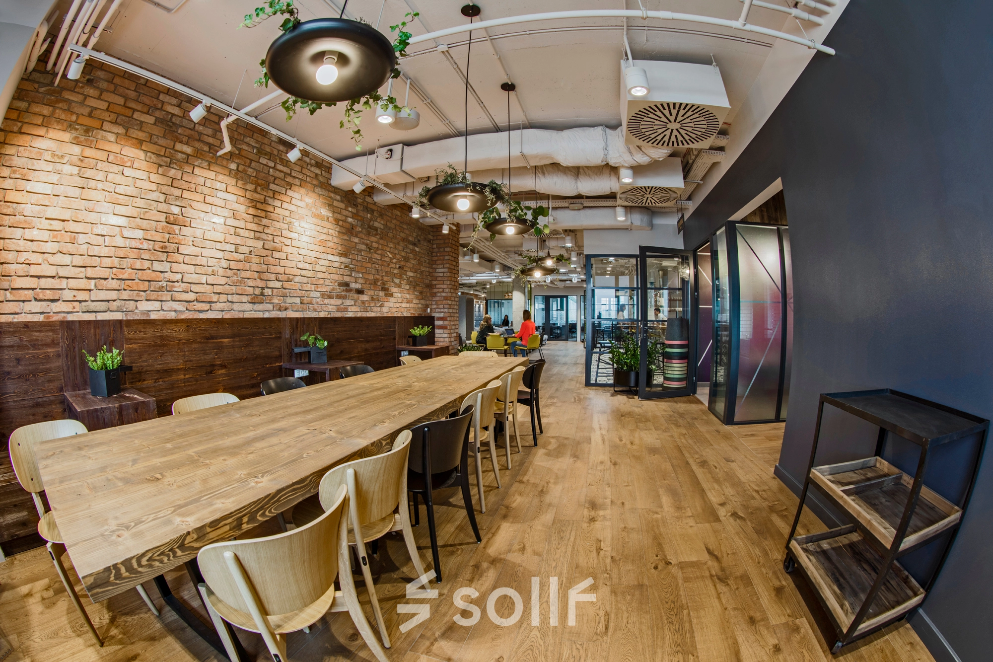 Inviting office space with a long wooden table and brick accent walls, perfect for collaborative work at Al. Jerozolimskie 181B, ideal for office space rental in Warsaw Ochota.