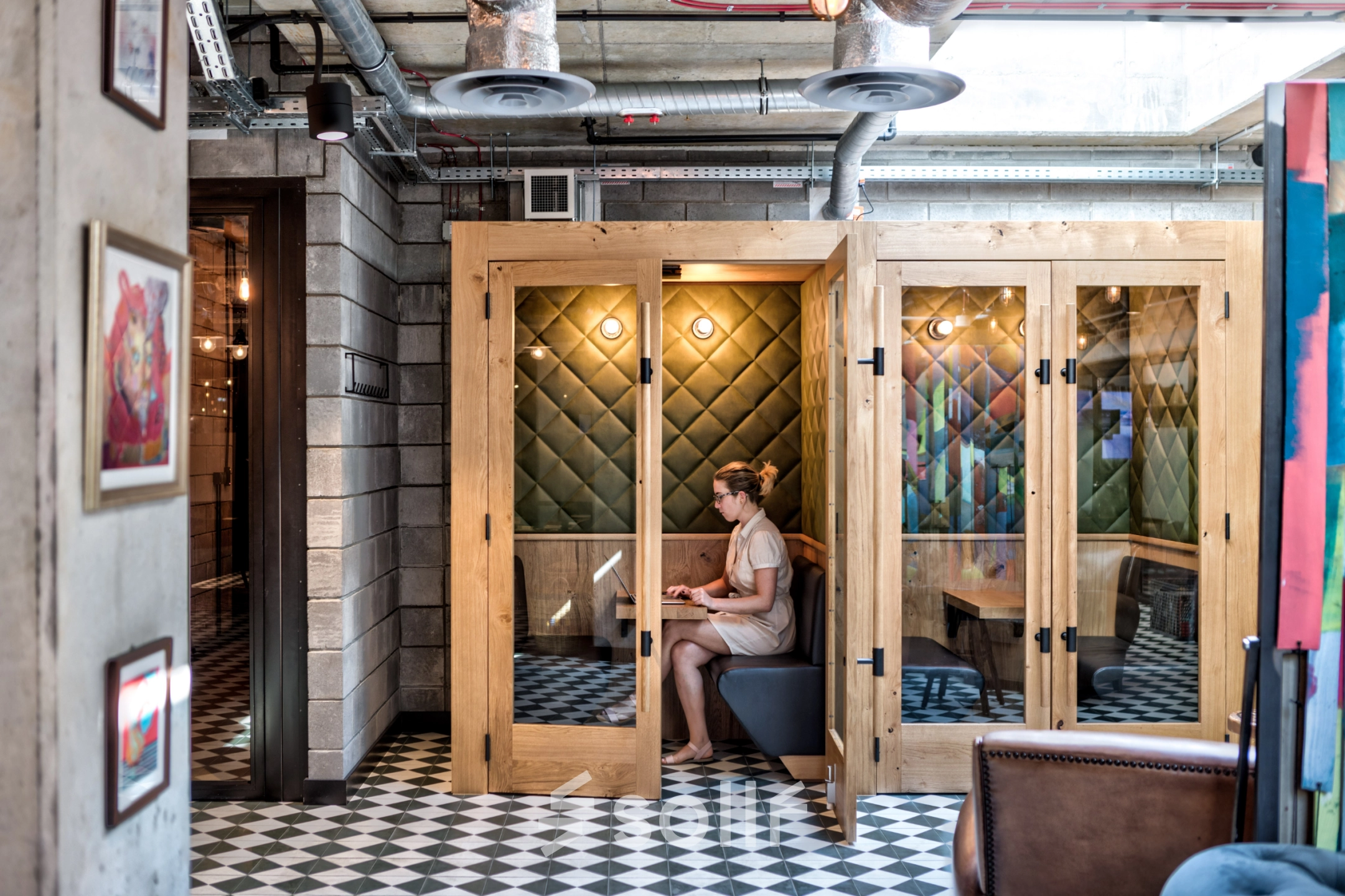 A person works on a laptop inside a cozy, wooden-paneled office space at Koszykowa 61, ideal for those seeking office space rental in Warsaw Śródmieście.