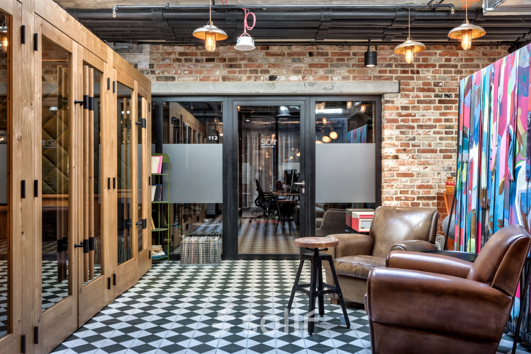 Furnished office space at Koszykowa 61 in Warsaw Śródmieście featuring cozy chairs, patterned flooring, and modern decor with ample space for meetings.