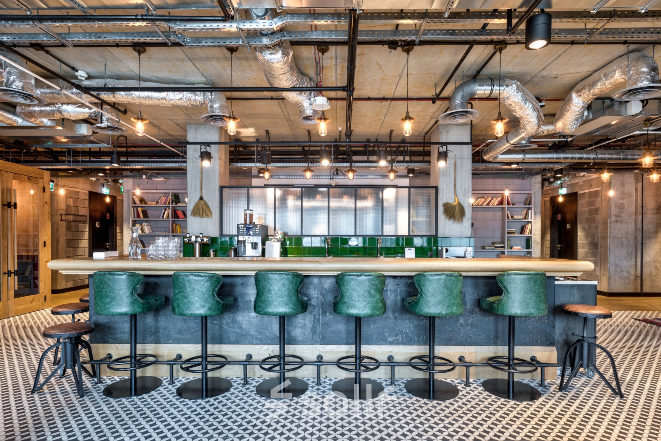Modern office space at Koszykowa 61 in Warsaw Śródmieście featuring a chic bar area with green stools and industrial design elements, ideal for office space rental.