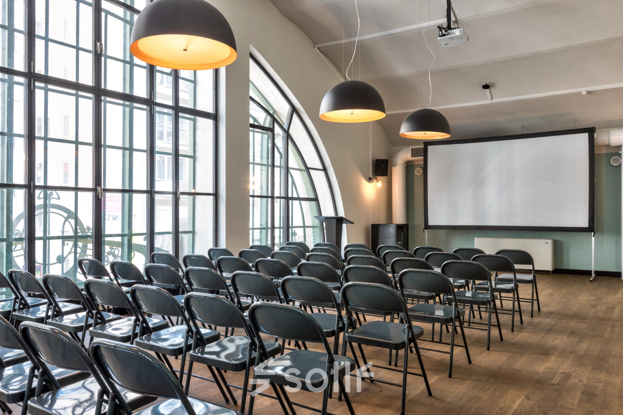 Spacious office to rent at Koszykowa 61, Warsaw Śródmieście, featuring a furnished conference room with rows of folding chairs and a large projection screen.