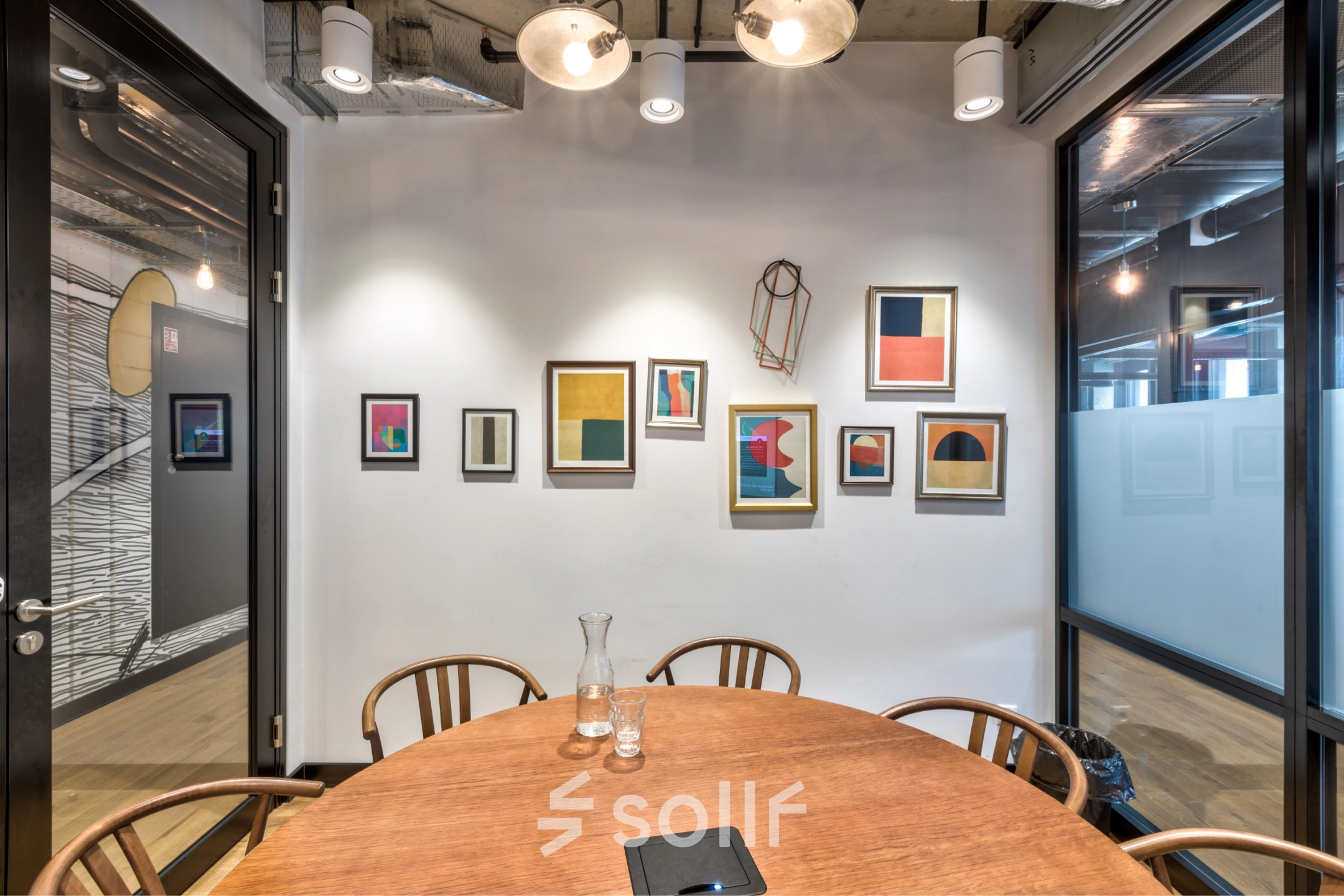Furnished meeting room with a round wooden table and artistic wall decor, perfect for those looking to rent office space in Warsaw Śródmieście.