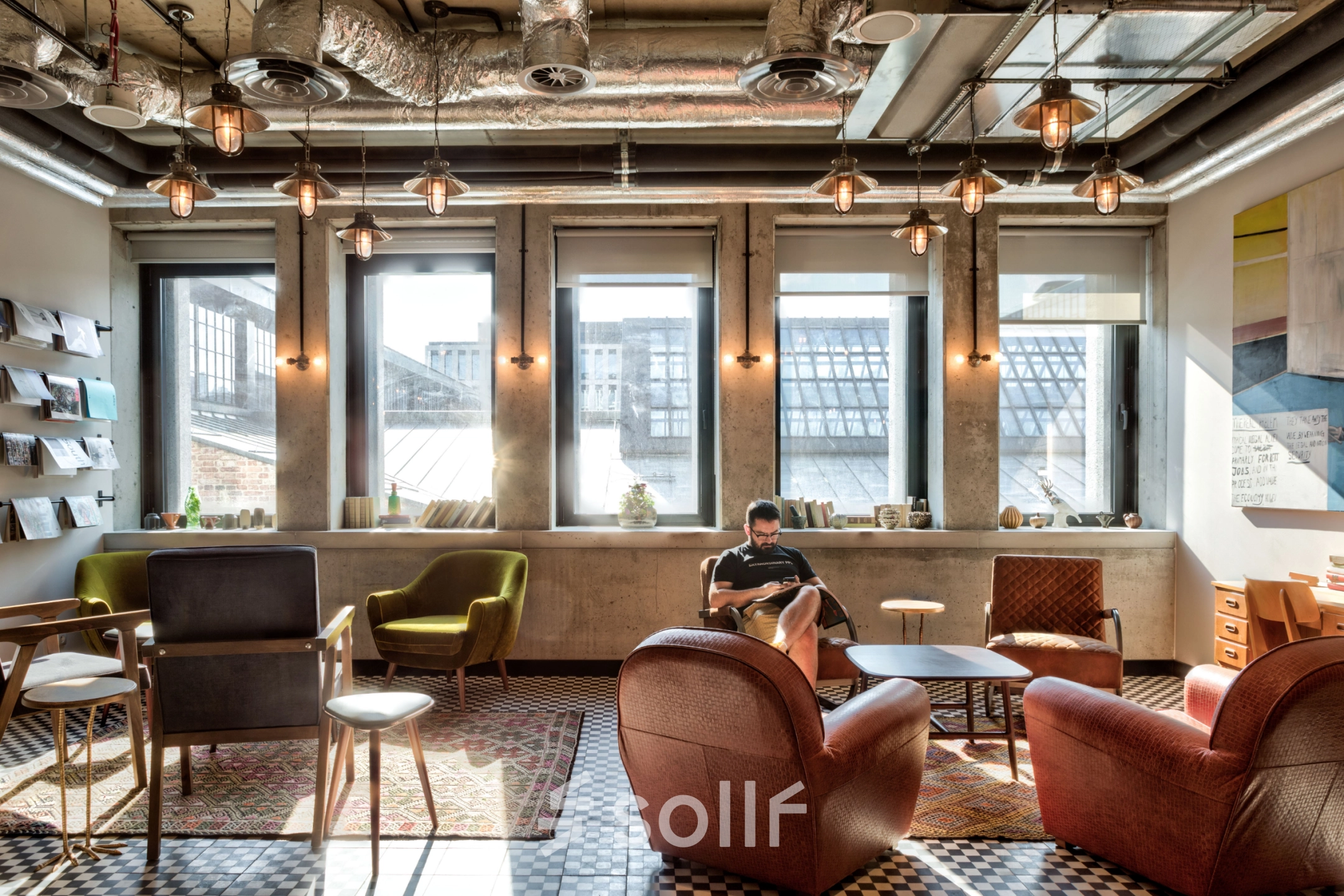Cozy office lounge at Koszykowa 61 in Warsaw Śródmieście, ideal for renting office space, featuring eclectic seating and industrial lighting.