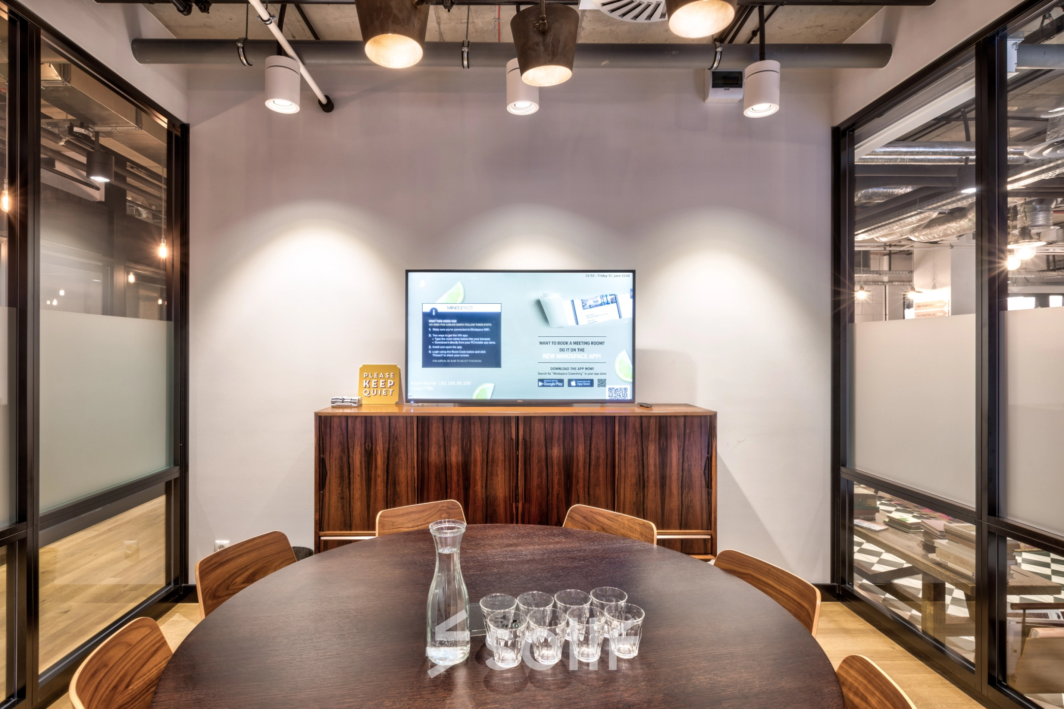 Furnished conference room at Koszykowa 65 in Warsaw Śródmieście, ideal for office space rental, featuring a round table and a presentation screen.