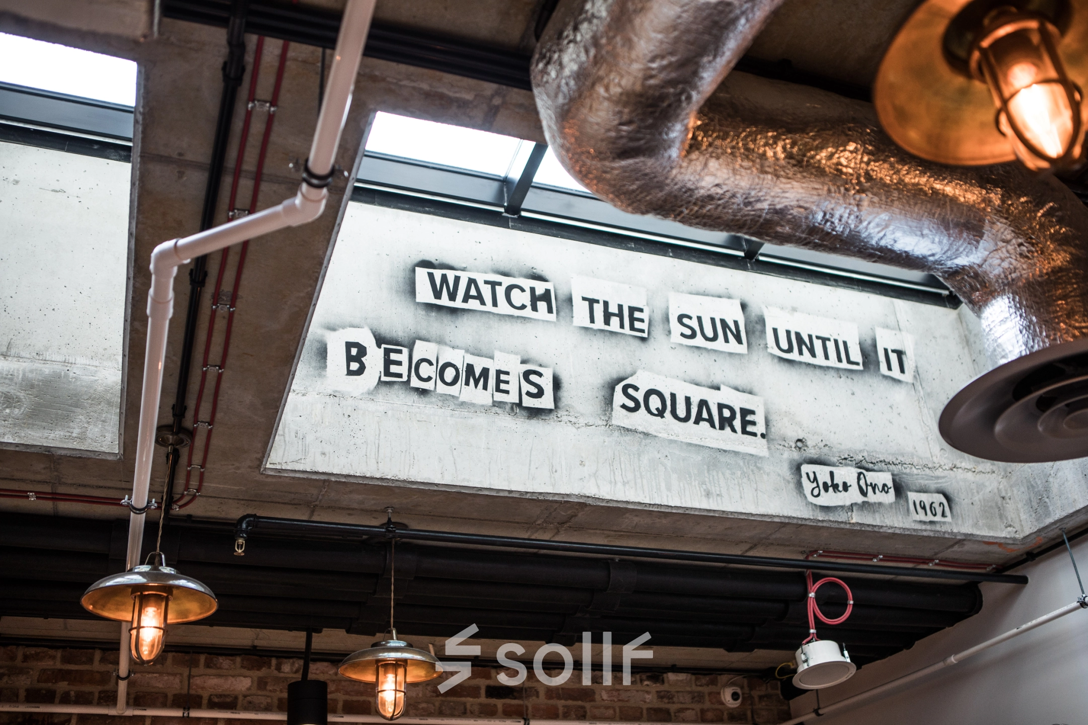 Interior office space at Koszykowa 65, Warsaw Śródmieście featuring industrial design elements and a skylight with a motivational quote. Ideal office to rent for creative thinkers.