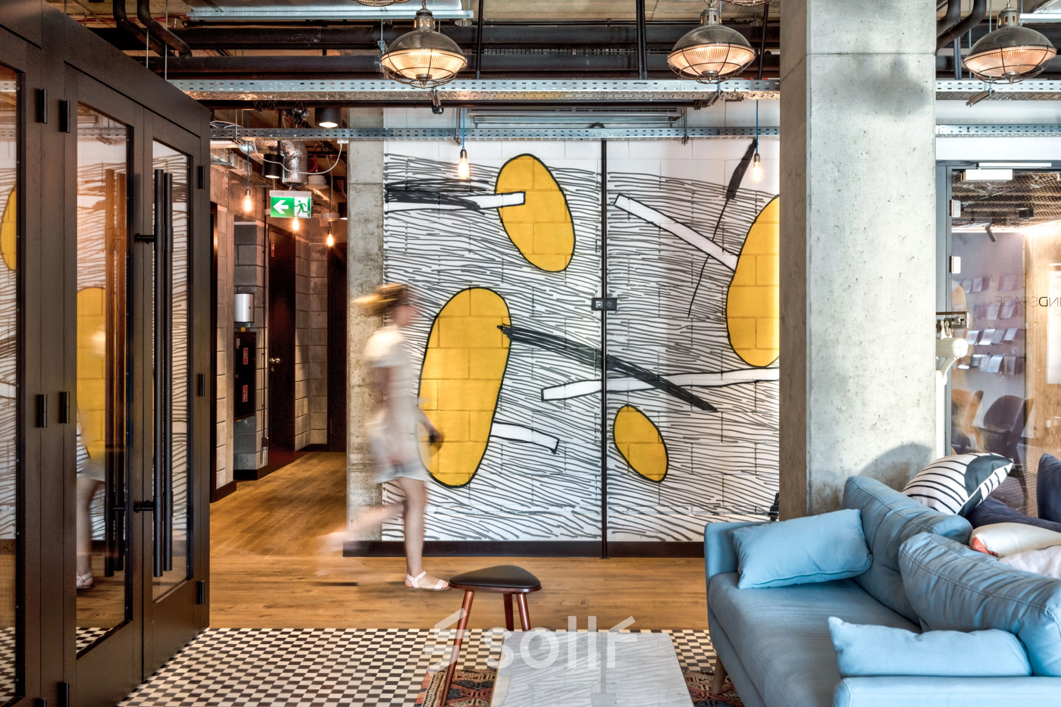 Furnished office space at Koszykowa 65 in Warsaw Śródmieście with modern decor and a casual seating area. A person is walking by, suggesting an active business environment.