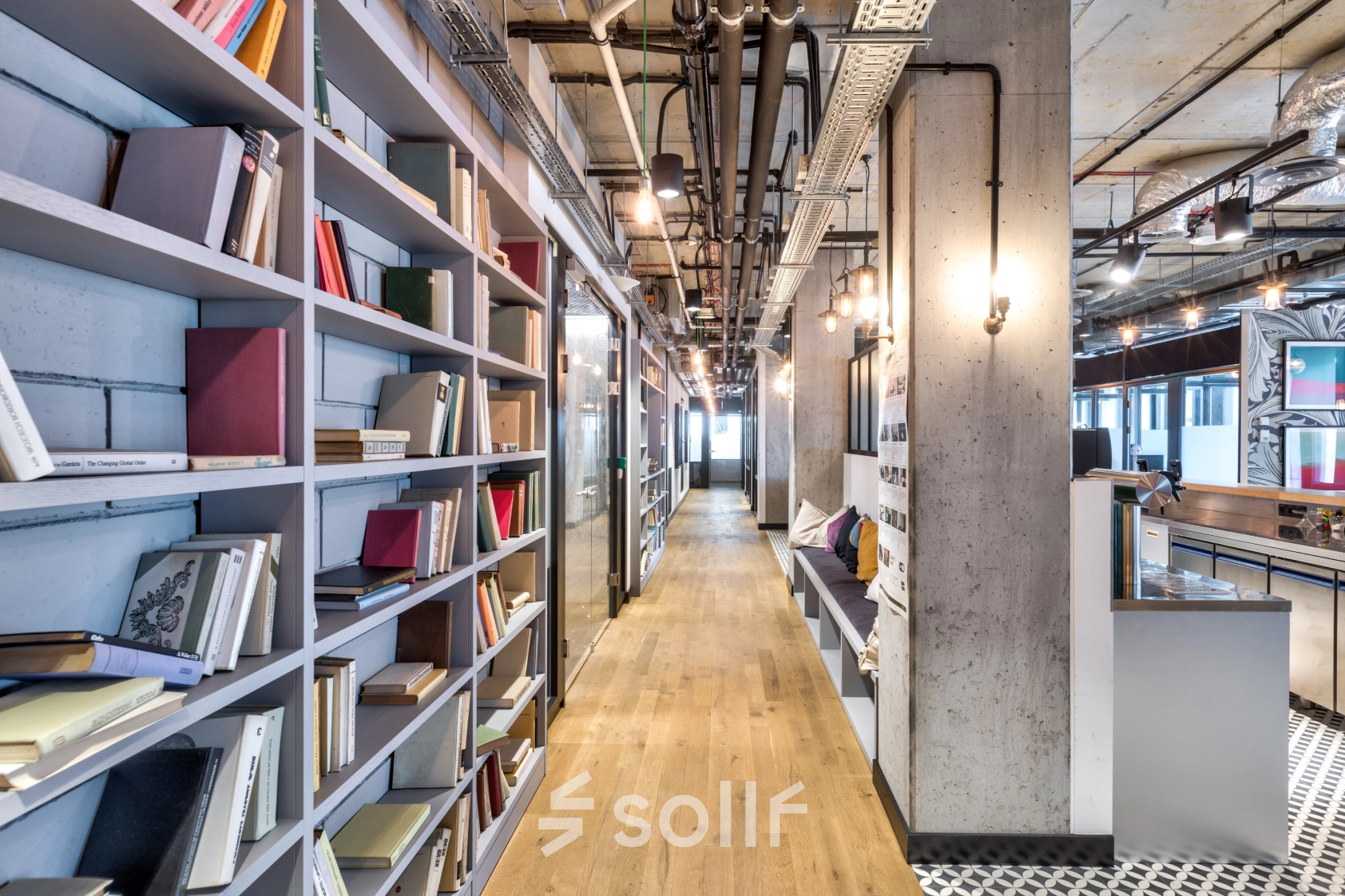 Bright office space to rent at Koszykowa 65, Warsaw Śródmieście, featuring bookshelves, a wooden floor, and modern lighting for an inviting atmosphere.