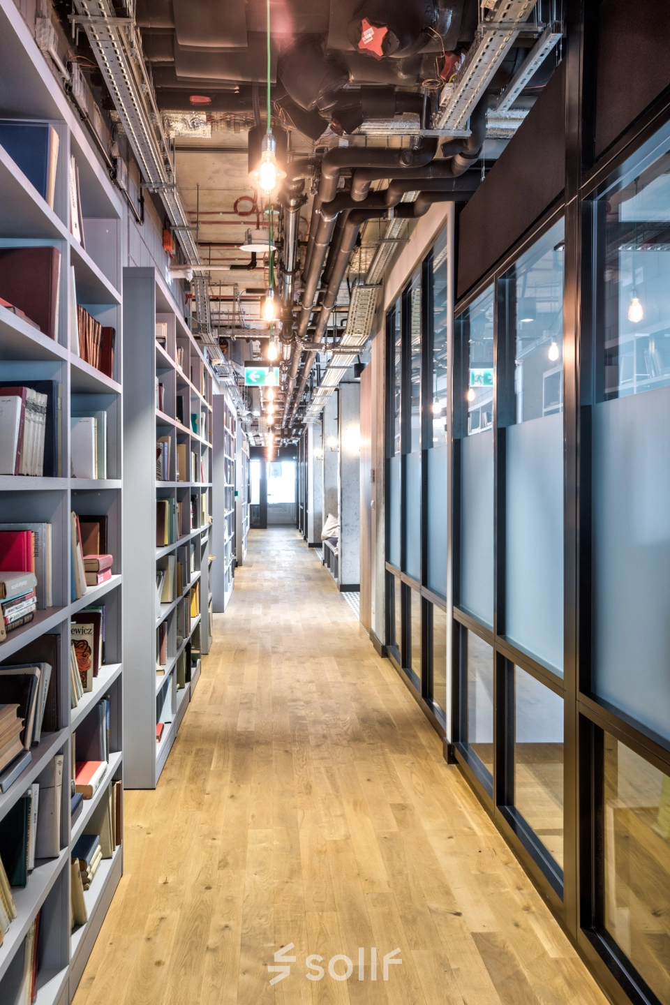A sleek office interior at Koszykowa 65, Warsaw Śródmieście with modern book shelves lining the hallway. Perfect for office space rental.