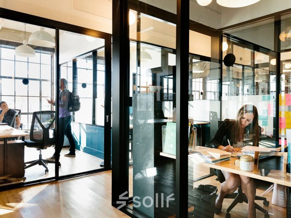 Business activities in a furnished office to rent on Krakowskie Przedmieście 13, Warsaw Śródmieście, showcasing modern workspaces with people engaged in discussions and work.