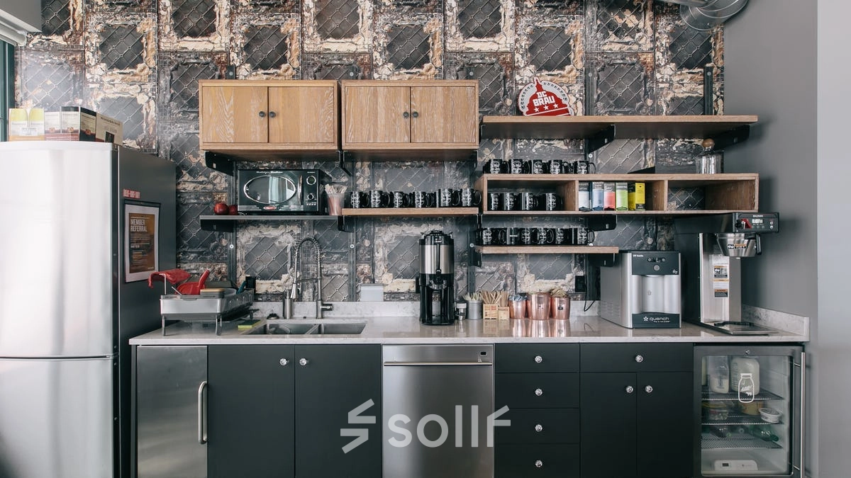 A modern kitchenette in an office space with coffee machines, shelves, and a stainless steel sink, ideal for office space rental in Warsaw Śródmieście.