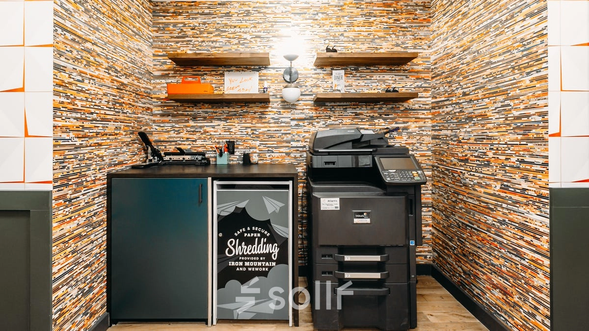 Furnished office space for rent featuring a printer and storage cabinet against a patterned wall, ideal for office space rental.