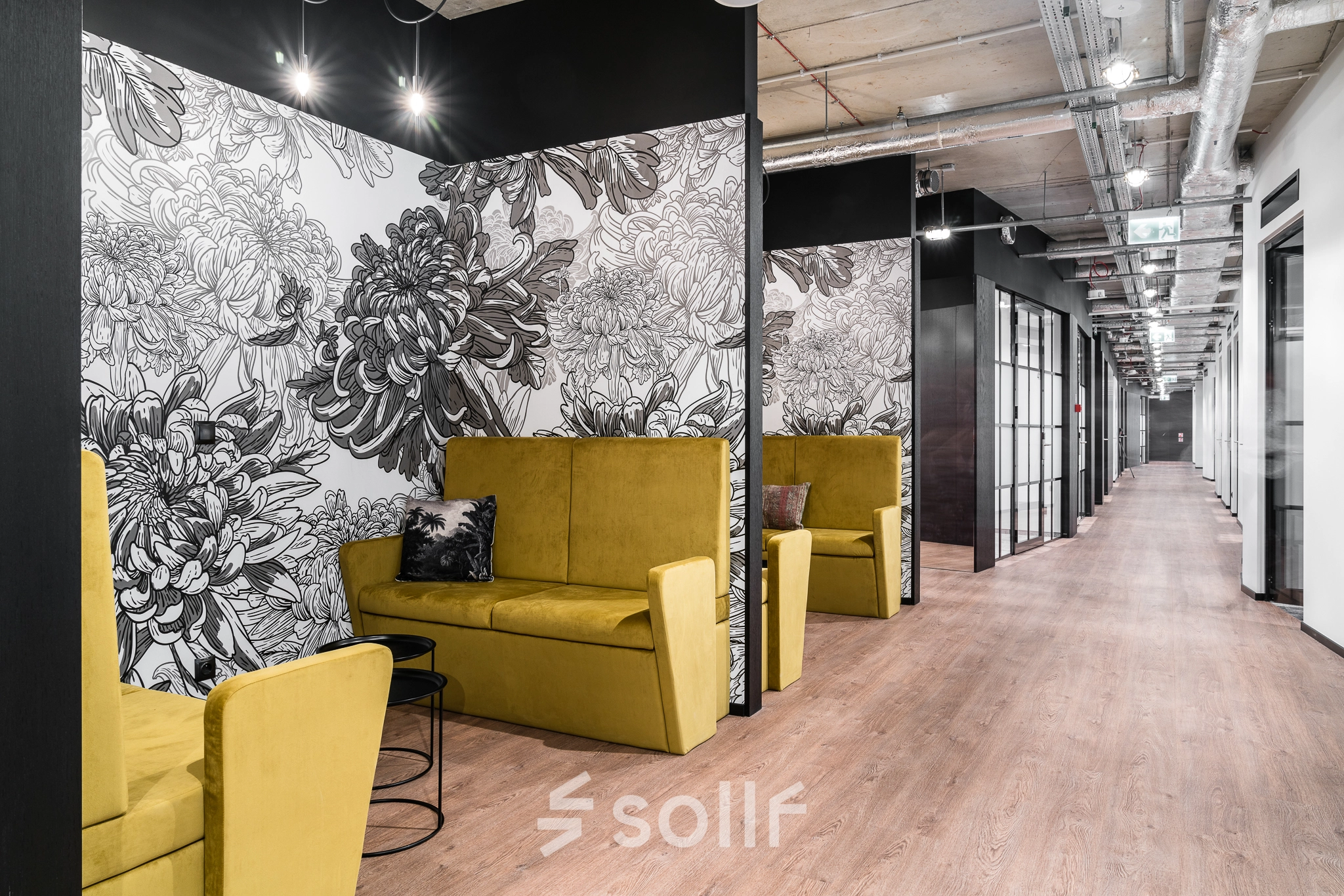 Modern office space in Warsaw's Śródmieście featuring stylish yellow seating, floral wall art, and a sleek hallway enhancing the office space rental experience.