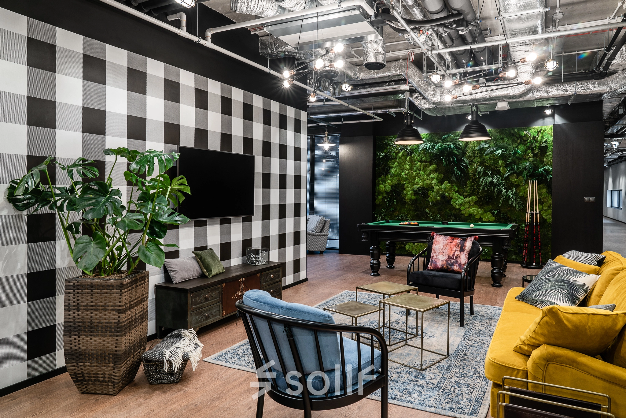 Stylish office space in Warsaw Śródmieście featuring cozy seating, a checkerboard wall, and a pool table, ideal for office space rental.