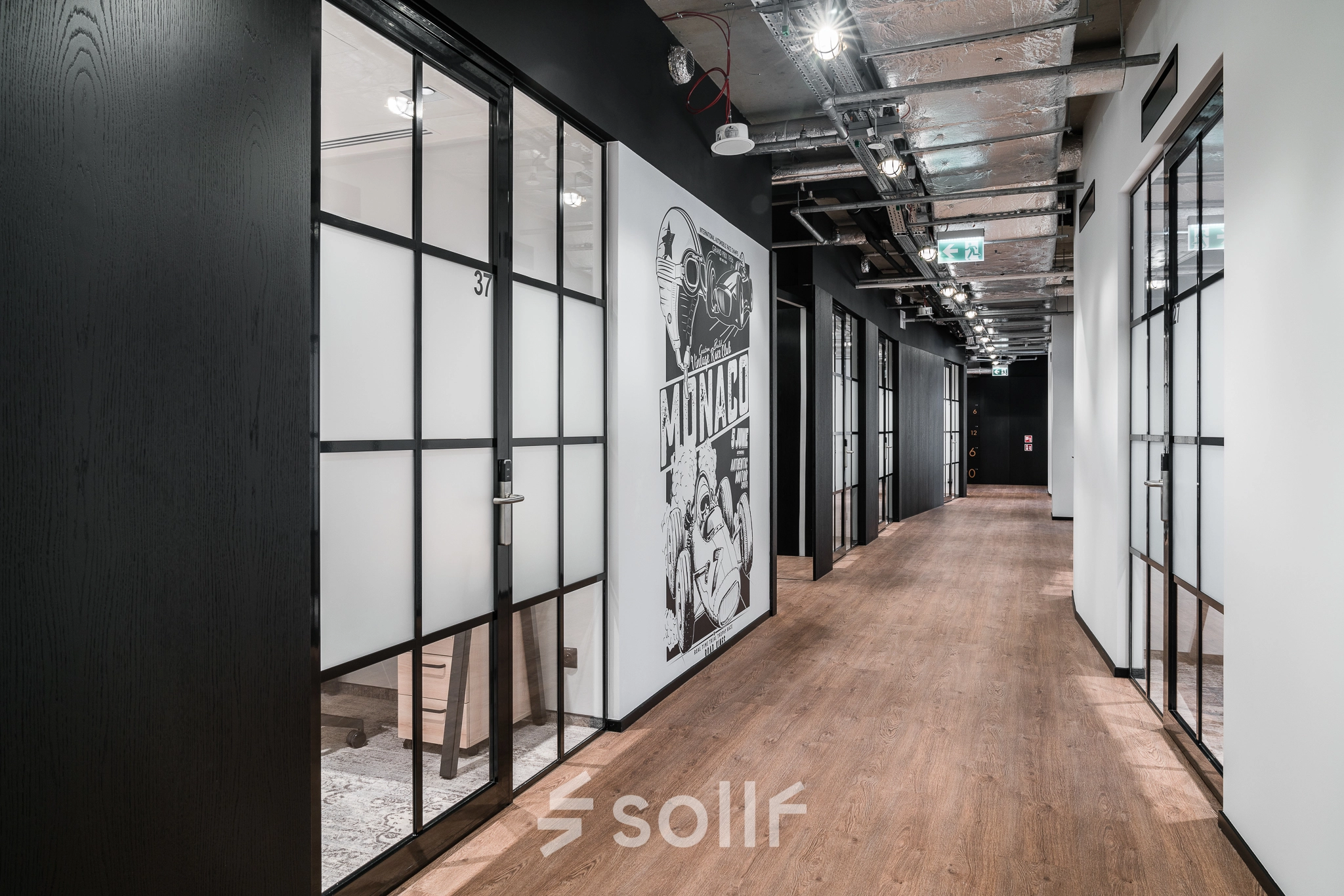 A modern office hallway with wooden flooring and glass-partitioned rooms at Plac Trzech Krzyży in Warsaw Śródmieście, perfect for office space rental.