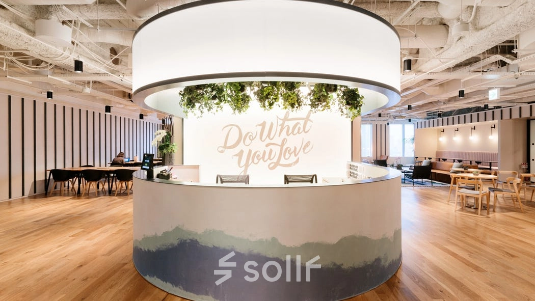 Modern office space rental at Grzybowska 60, Warsaw Wola featuring a circular reception desk with greenery and motivational signage.