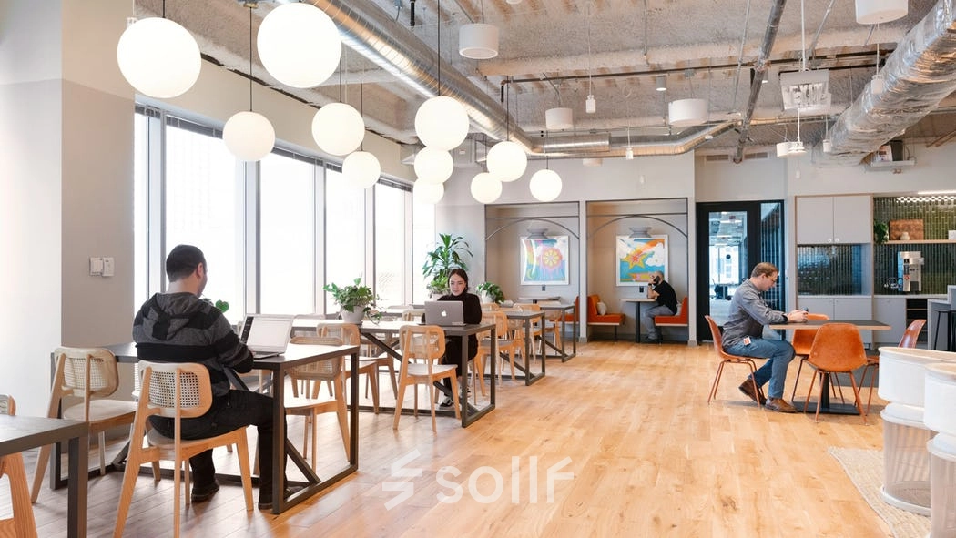 Spacious and modern office space rental at Rondo Daszyńskiego 2, Warsaw Wola, features people working on laptops at stylish wooden tables.