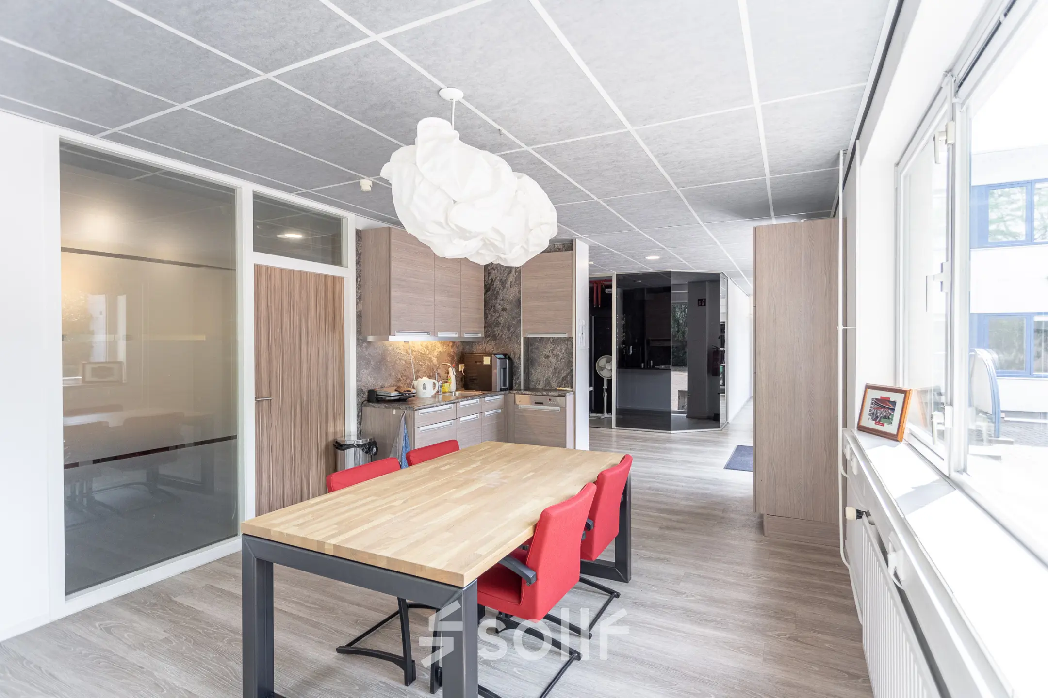 Bright office kitchen space with modern wooden tables and red chairs available for office space rental at Molenweer 2, Wateringen.