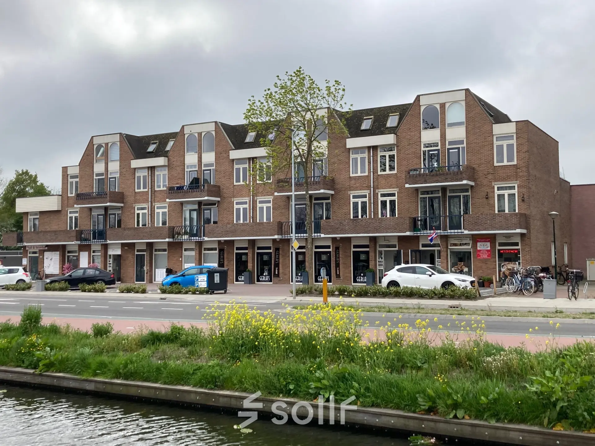 Exterior view of an office building at Boerendijk 8 in Woerden, showing multiple storefronts and parking options. Ideal spot for office space rental.
