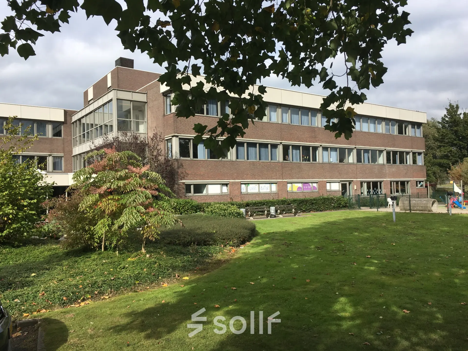 Exterior view of an office building at Houttuinlaan 4 in Woerden, surrounded by green lawns and trees, ideal for office space rental.