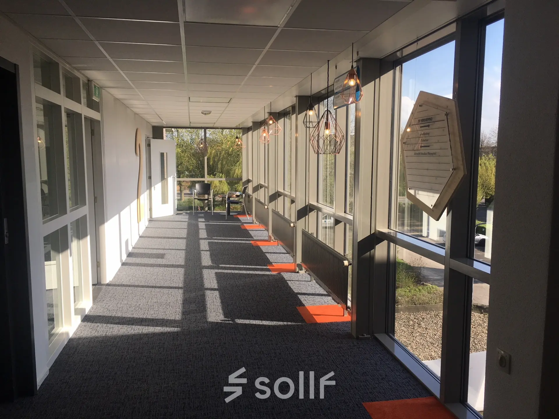 A bright hallway at Houttuinlaan 4 in Woerden, with modern lighting and large windows. Ideal for those looking to rent office space with a professional ambiance.