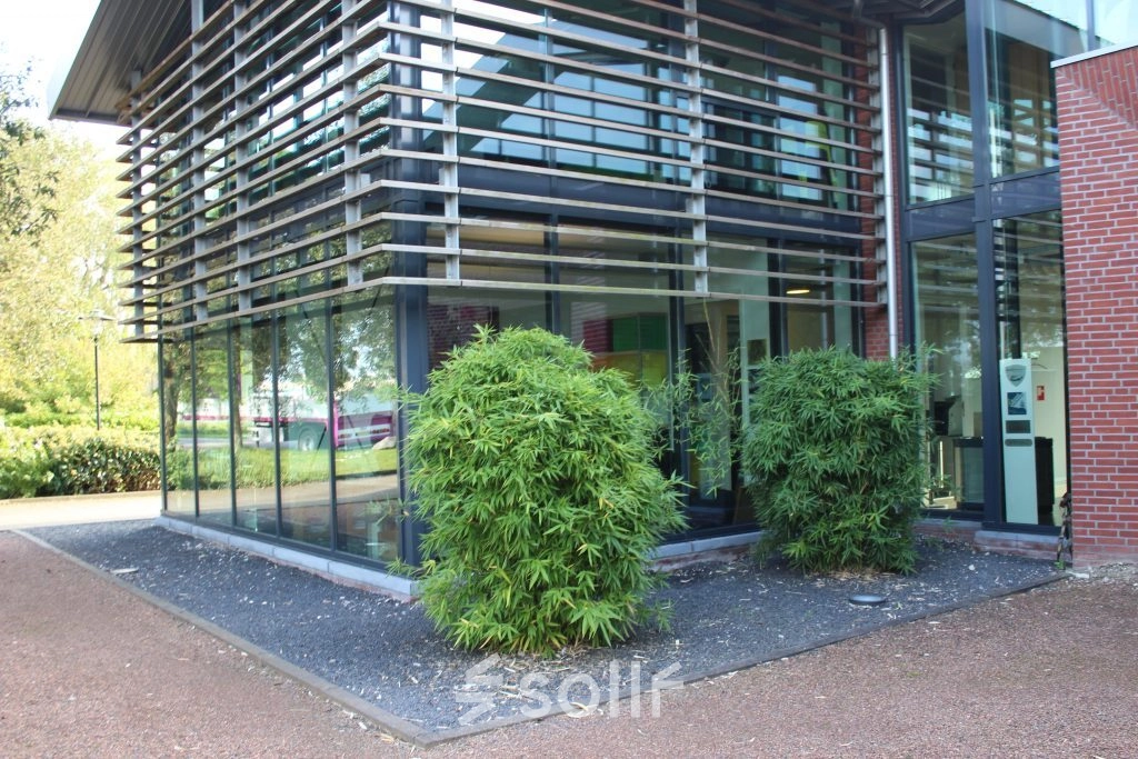 Exterior view of office building at M.A. Reinaldaweg 2d, Woerden with modern glass facade and lush greenery, ideal for office space rental.