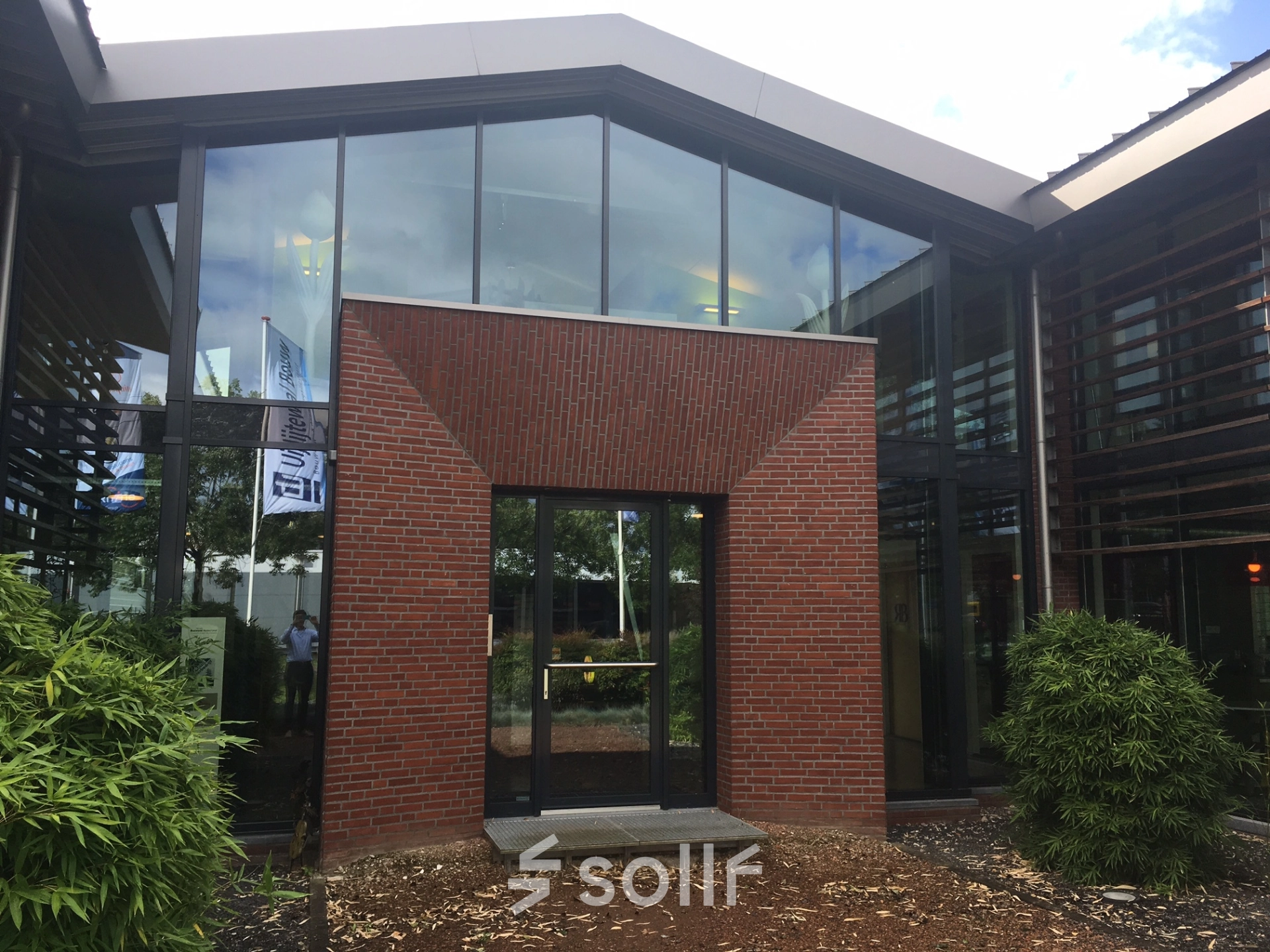 Modern exterior view of office building at M.A. Reinaldaweg 2d, Woerden, featuring large glass windows and brick facade, ideal for office space rental.