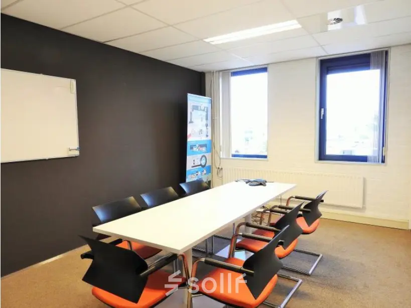 Bright office space at Pompmolenlaan 9, Woerden, featuring a meeting table and chairs near large windows, ideal for office space rental.