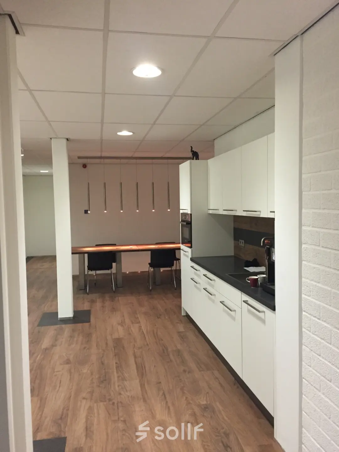 Bright office space at Pompmolenlaan 9, Woerden, featuring a sleek kitchen nook and wooden flooring, perfect for office space rental.