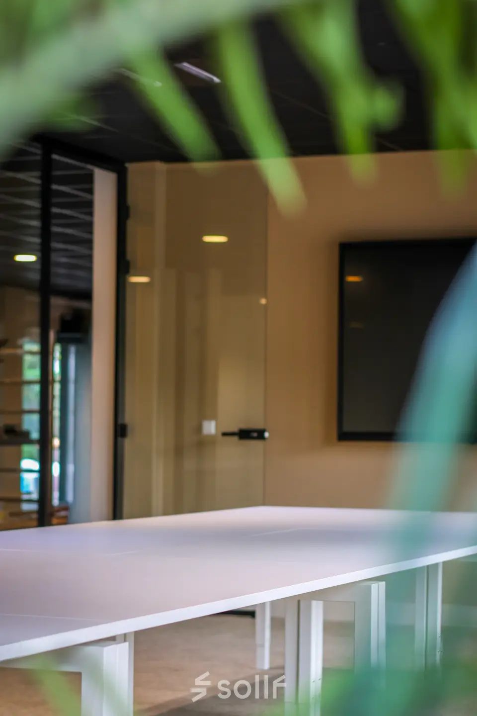 Modern office space with white tables and a large screen, suitable for workspaces available for office space rental.