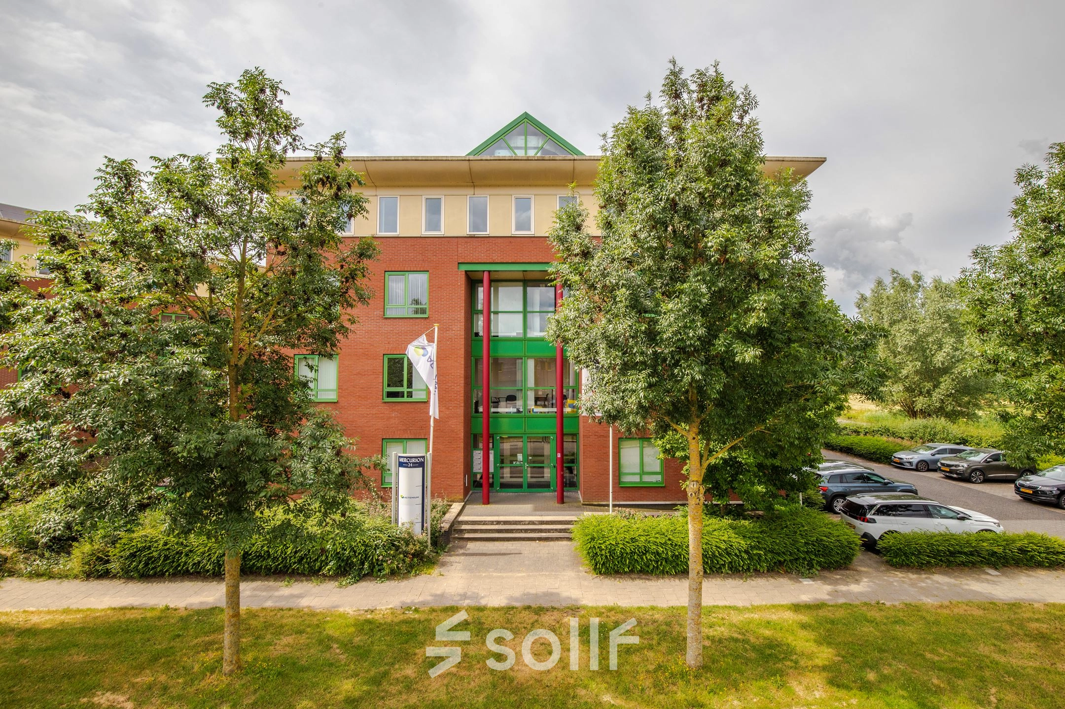 Exterior view of Mercurion 24 in Zevenaar, showcasing a red-brick office building with green accents, ideal for office space rental.