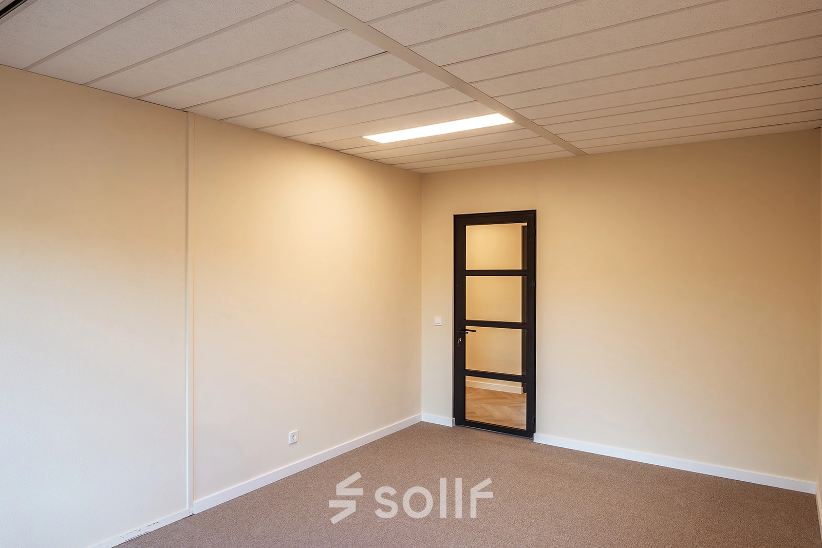Empty office space at Mercurion 24, Zevenaar, ready for rent. Features beige walls and a simple carpeted floor, ideal for personalizing your workspace.