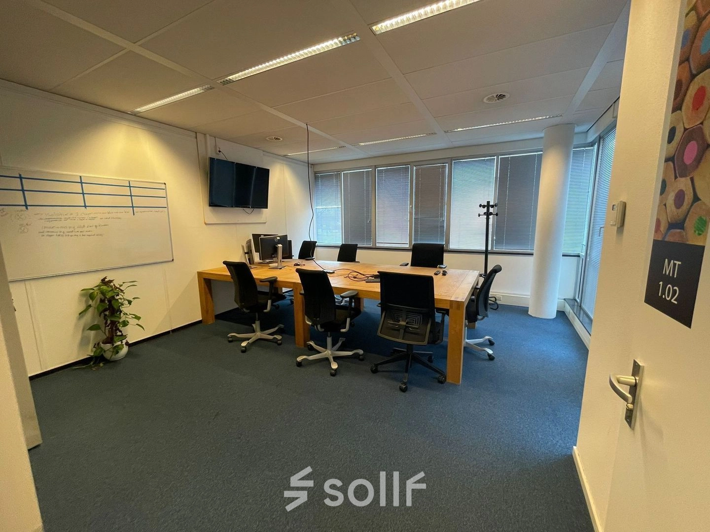 Modern conference room at Baron de Coubertinlaan 35, Zoetermeer, featuring a large wooden table, office chairs, a whiteboard, and a flat-screen TV, ideal for office space rental.