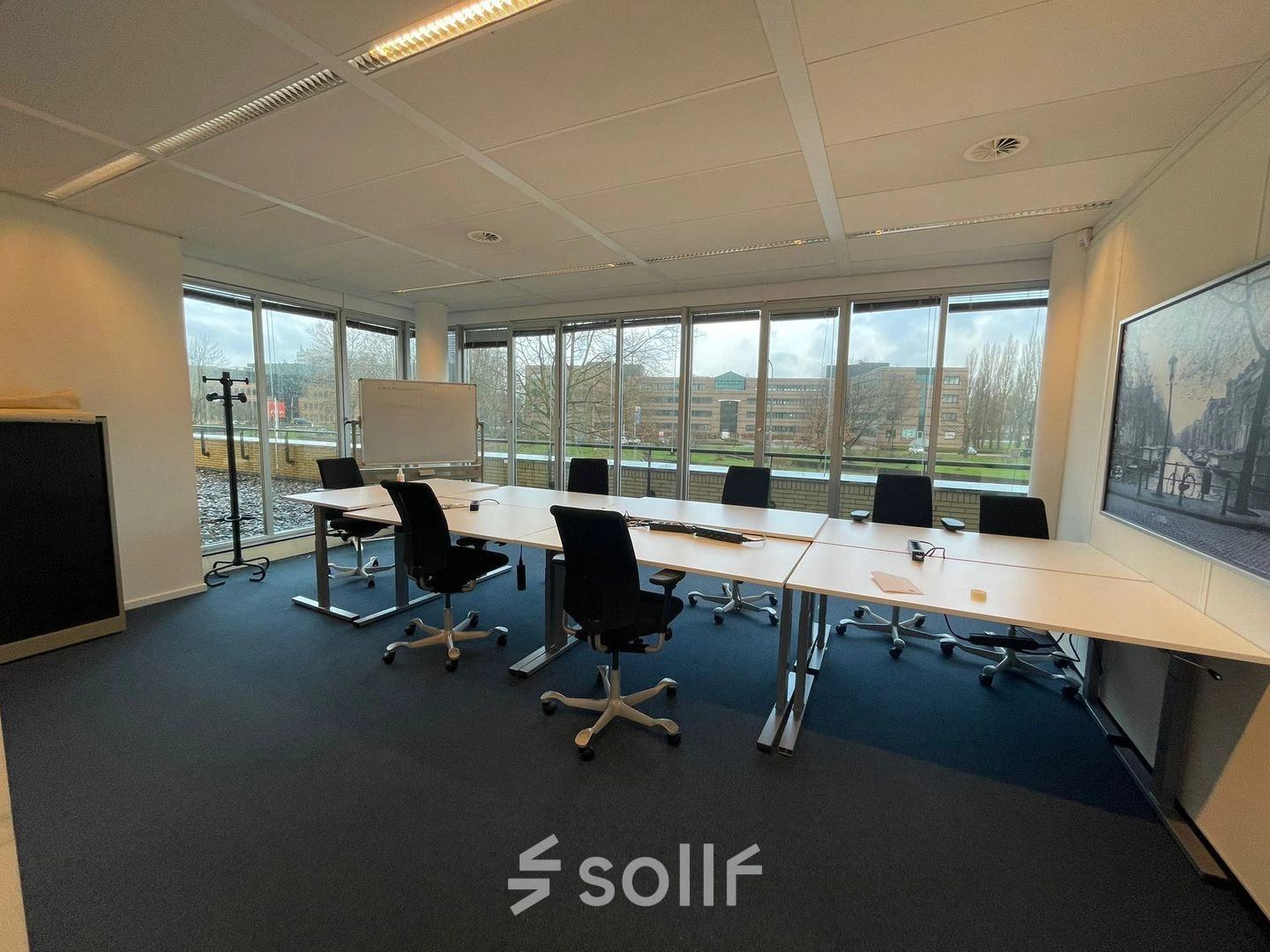 Spacious office to rent at Baron de Coubertinlaan 35, Zoetermeer, featuring a large table with chairs, ready for meetings. Ideal for office space rental with expansive windows letting in natural light.