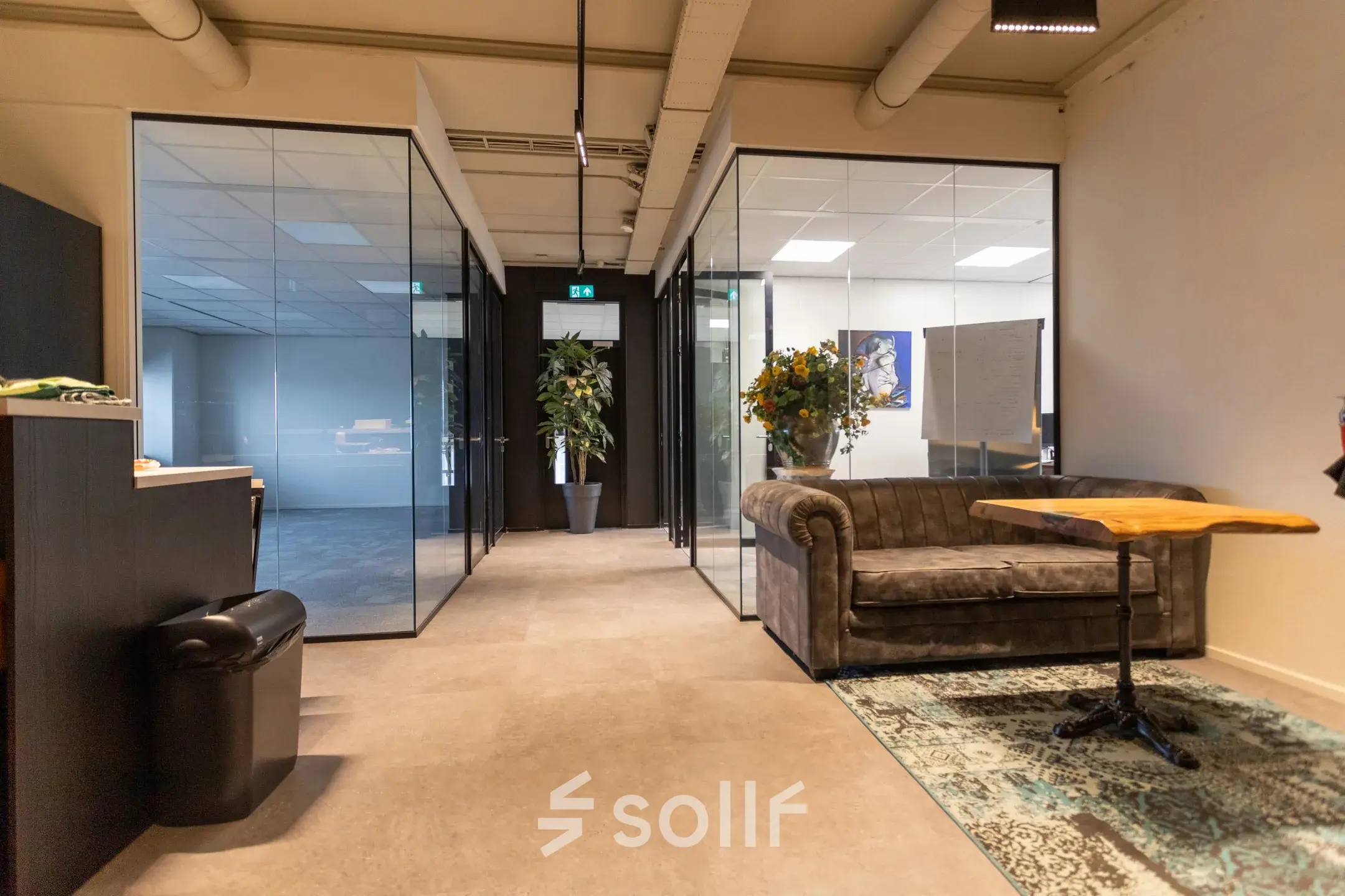 Office to rent at Boerhaavelaan 40 in Zoetermeer featuring a cozy furnished interior with a sofa and a wooden table, surrounded by glass-walled rooms and decorative plants.