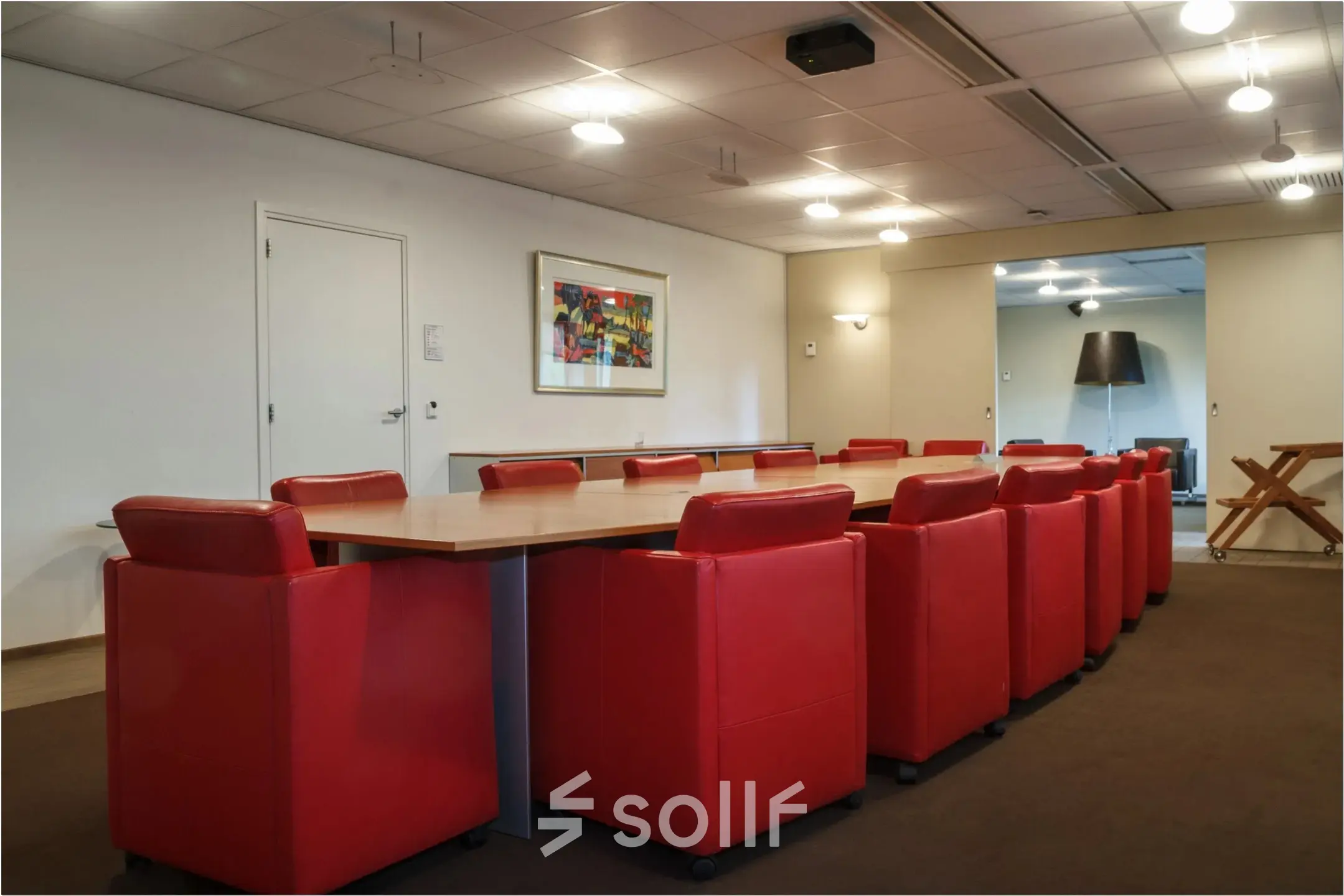 Furnished office conference room at Bredewater 26, Zoetermeer, available for rent. The room features a large table surrounded by red chairs, making it suitable for meetings.