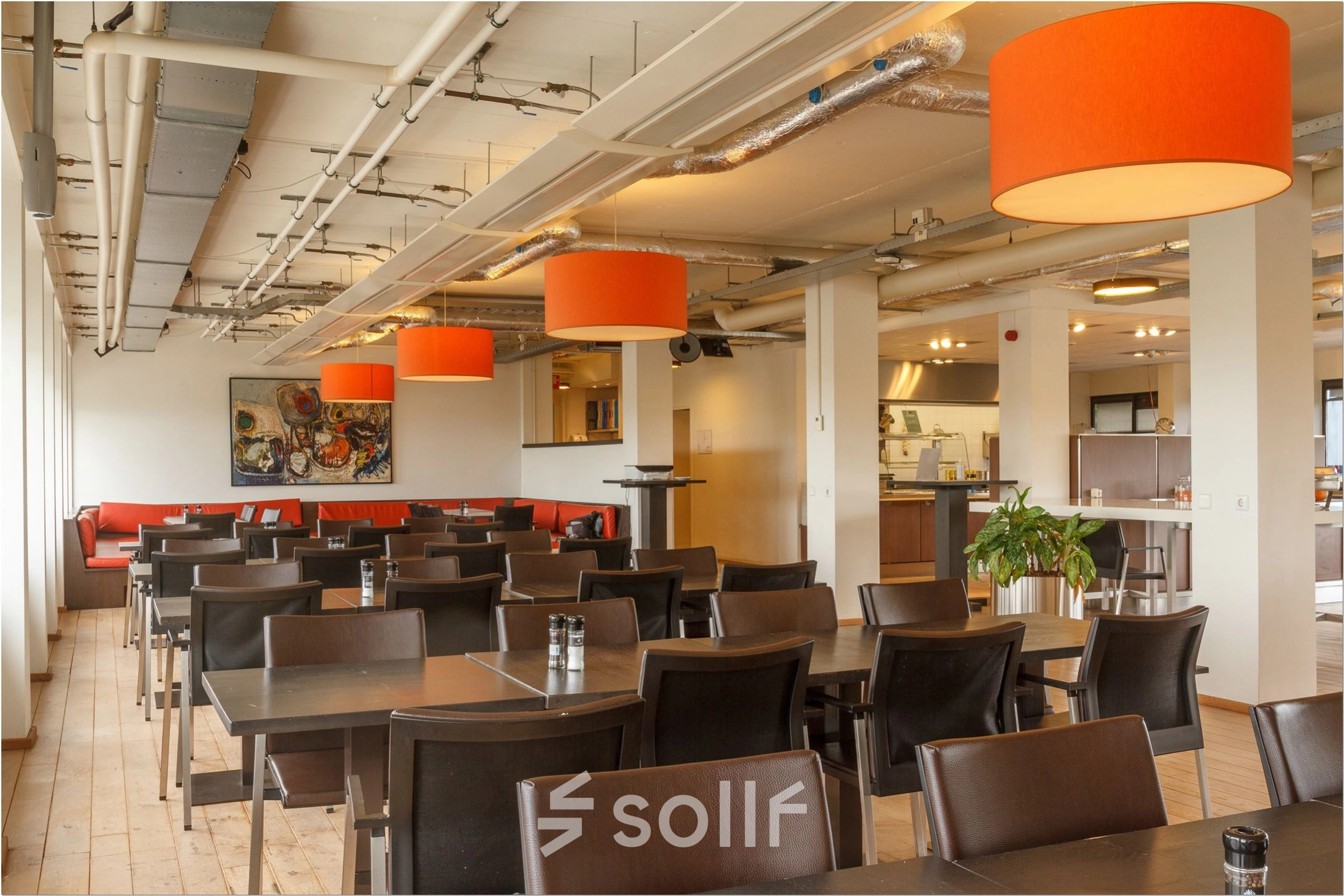Spacious, furnished office space rental featuring a bright, open floor plan with modern tables and chairs, accent lighting, and art decor at Bredewater 26, Zoetermeer.