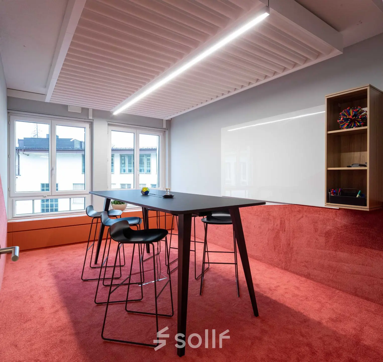 Stylish office space with a red carpet, high table, and modern stools, located at Talacker 41 in Zürich Center. Ideal for office to rent needs.