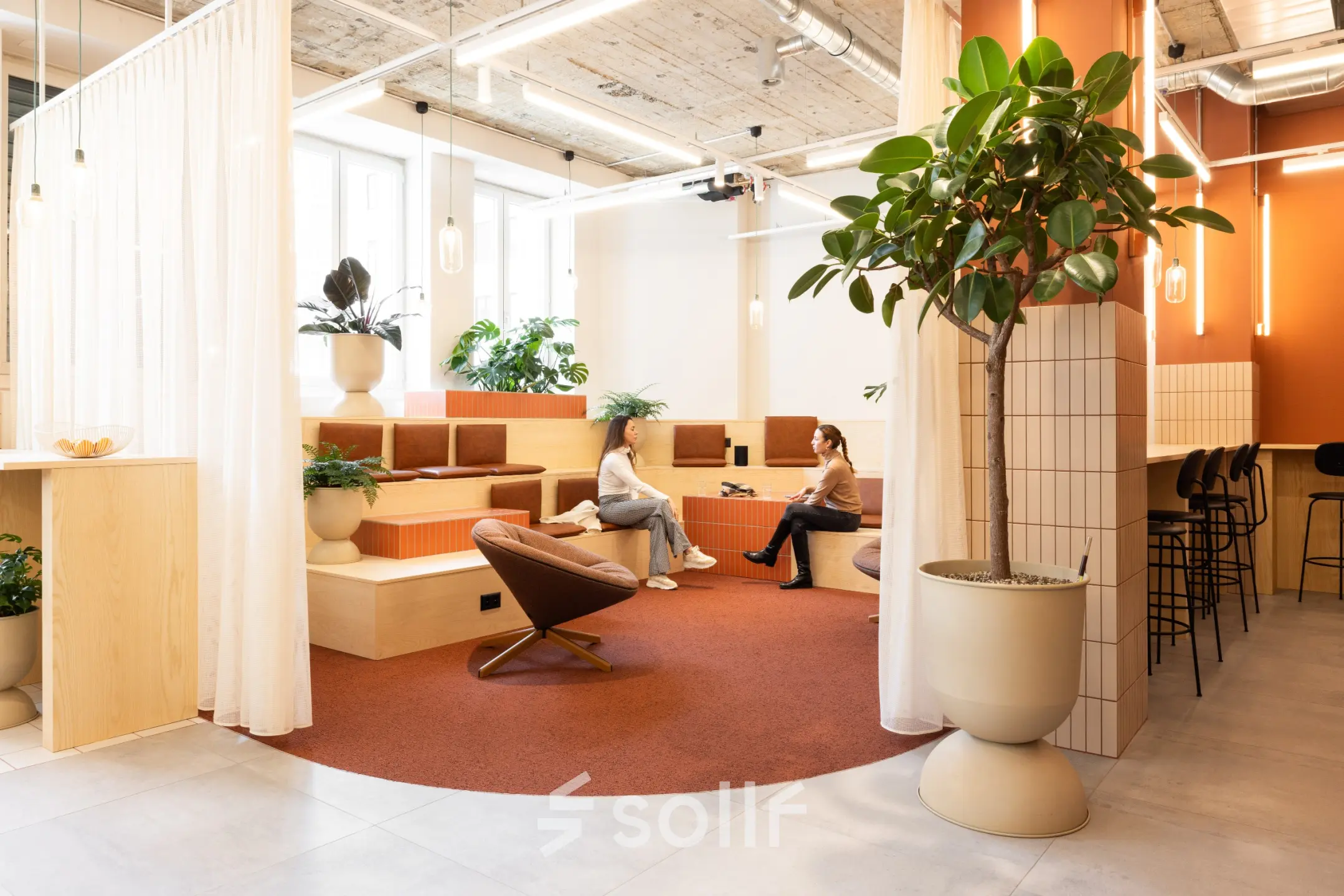Stylish office space at Beethovenstrasse 48, Zürich Enge, featuring modern furnishings and two people discussing work in a cozy seating area, ideal for office space rental.
