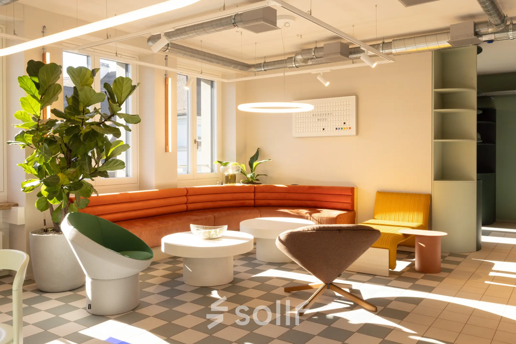 Bright office space with modern furnishings including a curved sofa, chairs, and decorative plants, located at Beethovenstrasse 48, Zürich Enge, ideal for office space rental.