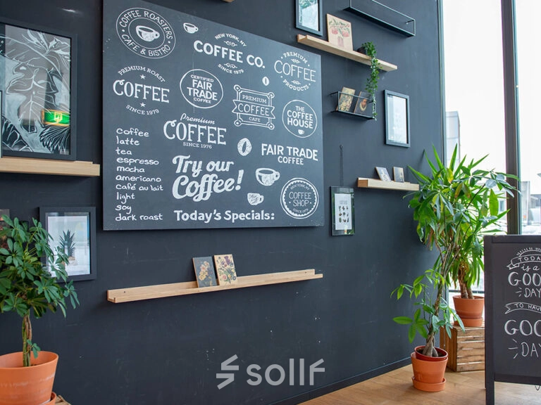 Interior of an office space at Assendorperdijk 1, Zwolle, featuring a black wall with coffee-themed decor and potted plants, suitable for office space rental.