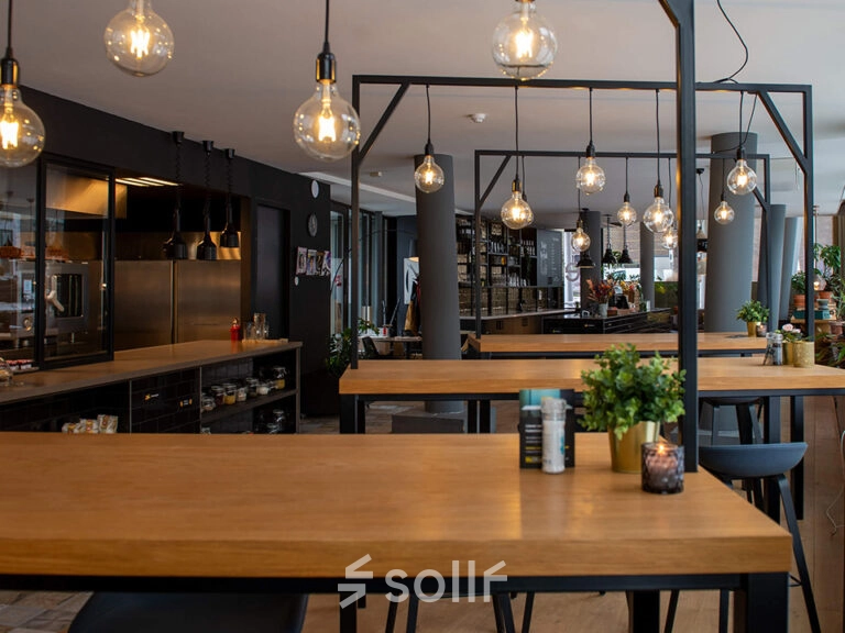 Modern office space rental in Zwolle with wooden tables and stylish lighting, offering a practical environment for business activities at Assendorperdijk 1.