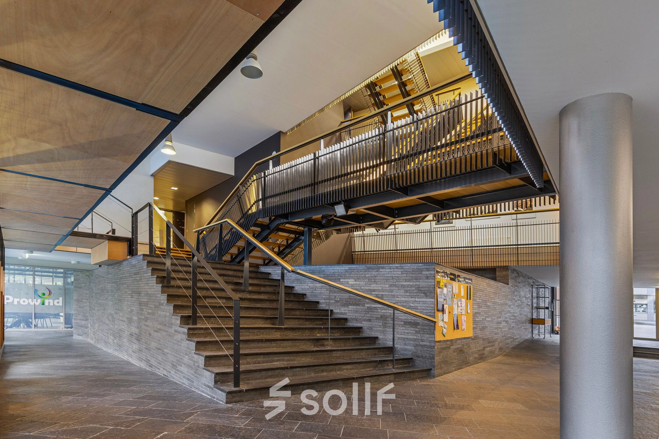 Spacious interior of an office space rental at Assendorperdijk 1, Zwolle, featuring modern architectural design with a striking staircase, ideal for a dynamic office to rent.
