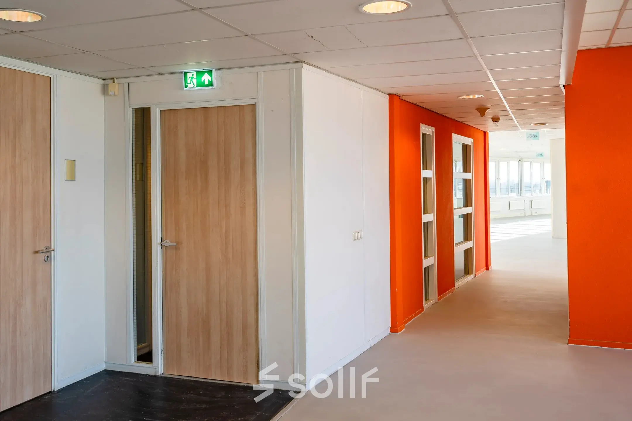 Bright hallway at Dokter van Deenweg 1 in Zwolle, showcasing vibrant orange walls and multiple doorways, ideal for office space rental.