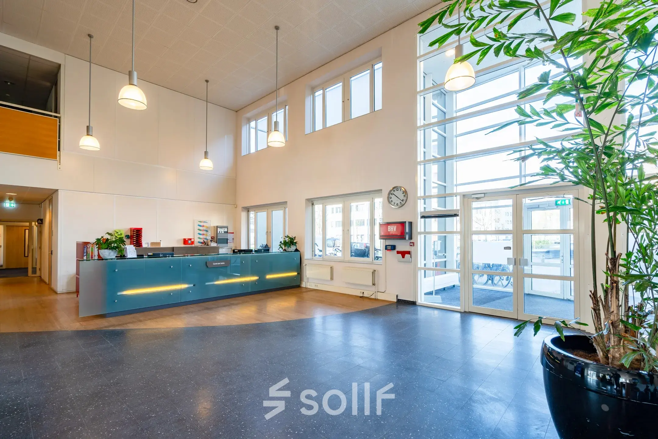 Spacious office entrance at Dokter van Deenweg 1, Zwolle, featuring a reception desk next to large windows with natural light, perfect for office space rental.