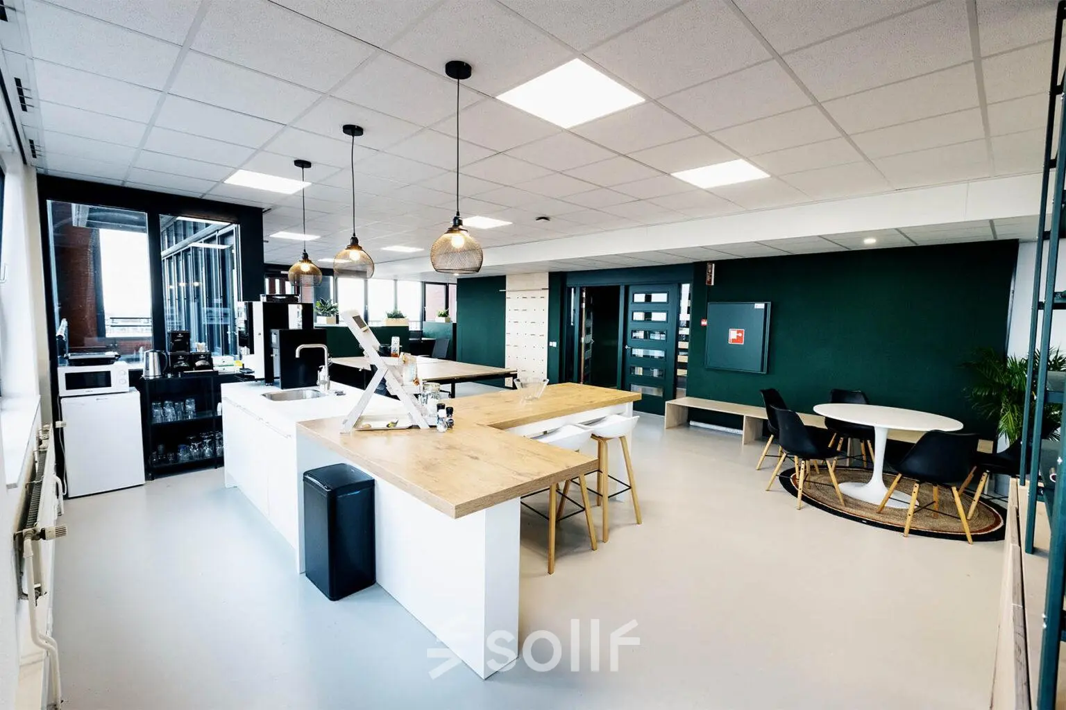 Furnished office space for rent at Hanzeplein 11-27, Zwolle, featuring modern design with a central countertop, seating area, and large windows.