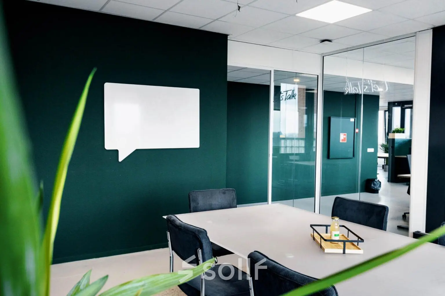 Modern office interior at Hanzeplein 11-27, Zwolle, featuring a sleek meeting table and chairs, ideal for office space rental. The dark green walls add a professional touch.