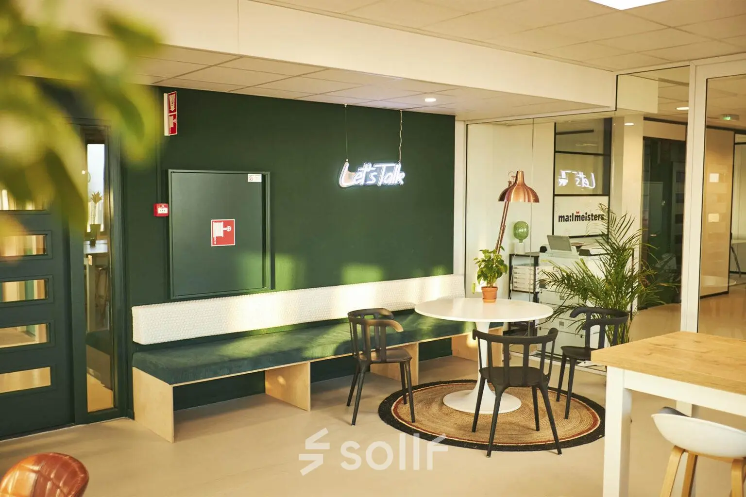 Cozy office space rental at Hanzeplein 11-27 in Zwolle, featuring seating and a neon sign saying 'Let’s Talk'. Ideal for businesses seeking a friendly office to rent.