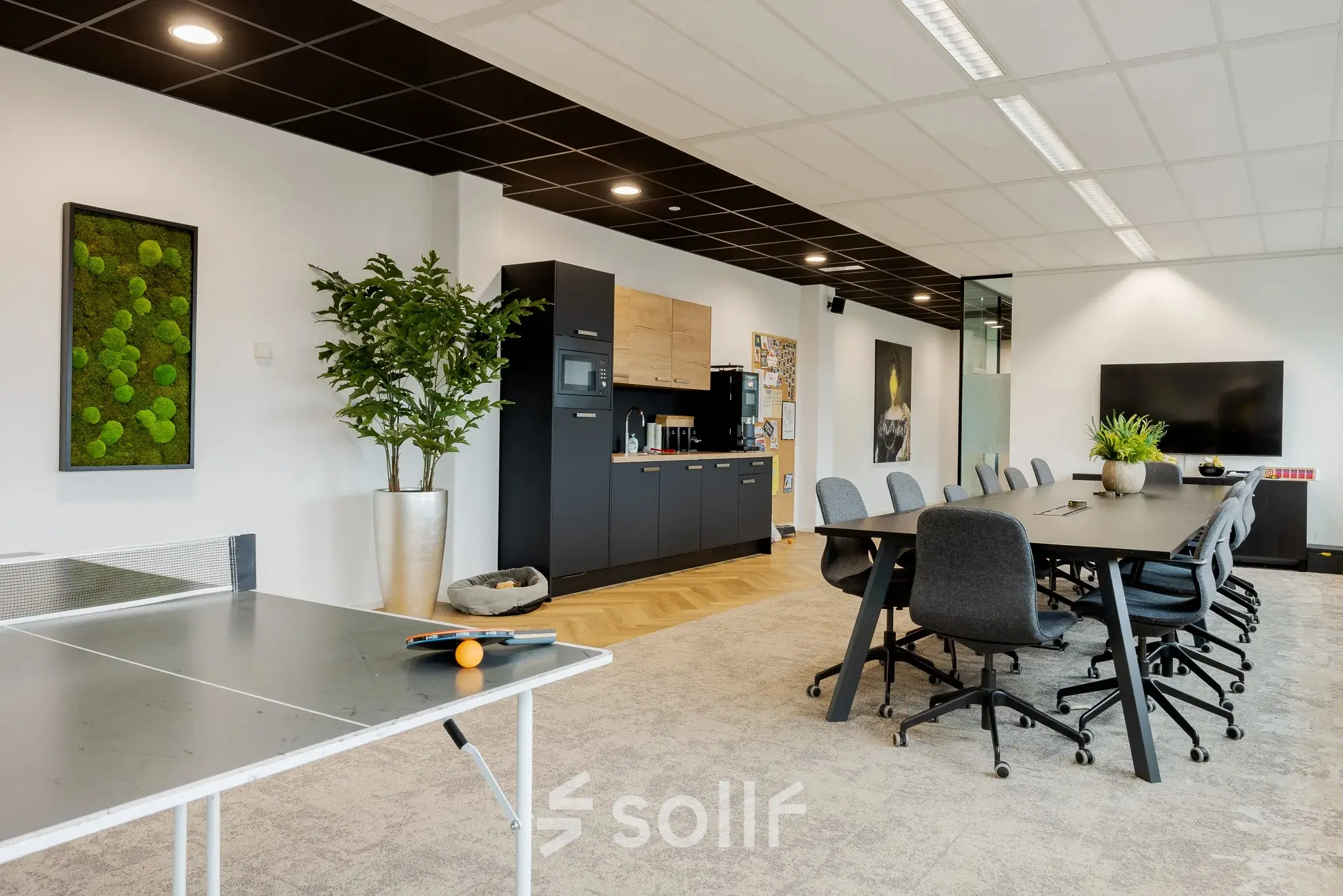 Modern office space with large tables and ergonomic chairs, featuring a kitchen area and a ping pong table. Ideal for office space rental in Zwolle at Zuiderzeelaan 15-25.