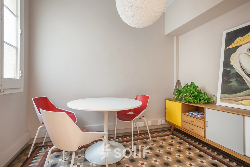 Espacio de trabajo iluminado y acogedor en alquiler de oficinas en Rambla de Catalunya, Barcelona Eixample, con mesa redonda, sillas rojas y suelo de mosaico.